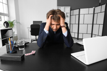 Tired young businessman suffering from headache in office