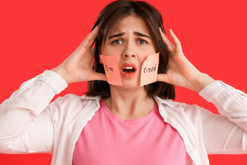 Beautiful young stressed woman and sticky notes with text I'M TIRED on red background. Stress Awareness Month - obrazy, fototapety, plakaty