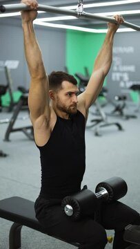 Vertical vide of male training back and hands muscles doing pulls weight exercise in a gym