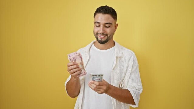 A smiling man examines egyptian currency against a yellow background.