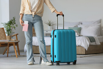 Woman with suitcase, passport and tickets in light hotel room - obrazy, fototapety, plakaty