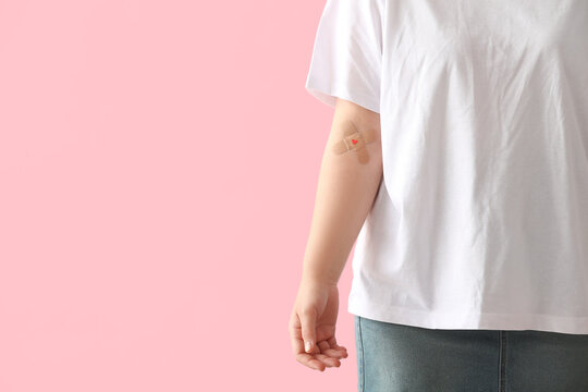 Blood donor with applied medical patches on pink background