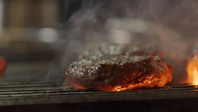 Cooking hamburgers on grill in kitchen with fire