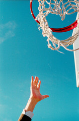 man's hand reaching for basketball hoop