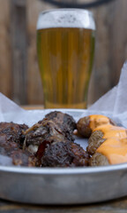 American food. Closeup view of delicious meatballs with covered in crispy bacon with baked potatoes with cheddar cheese sauce and a pint of beer. 