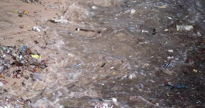 Sandy beach polluted with plastic waste. Global environmental disaster, mountains of garbage on the beach that came from the ocean. Waste floats in the water. Avoid bags and plastic bottles.