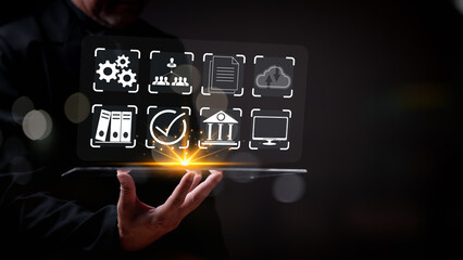 A man is holding a tablet with a screen displaying a variety of icons