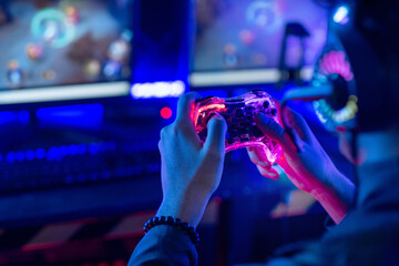 Close-up, video game console controller in gamer hands at colorful neon light living room at night, E-sport streaming game online, selective focus © chomplearn_2001