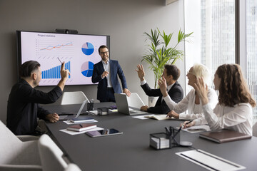Motivated professional team members gathered together at corporate seminar raise hand, voting...