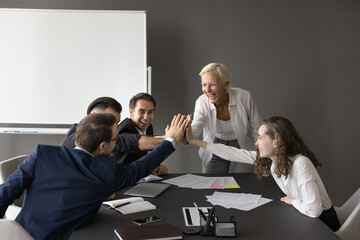 Group of young and mature enthusiastic executives celebrate successful project completion, with...