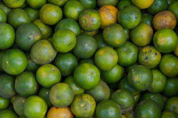 Fresh green bitter oranges fill the frame, showcasing healthy fruits at a local market.