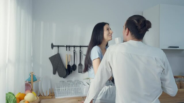 Romantic young couple drinking coffee together in the kitchen, having a great time together in a morning