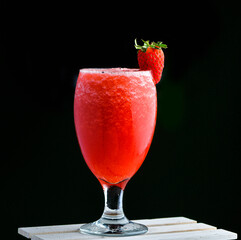 Fresh strawberry fruit juice in a glass with slice of fruit on top of the glass
