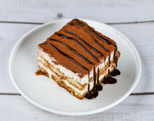 creamy soft Tiramisu dessert in a plate decorated with melted chocolate