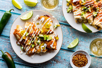 Plates of taquitos topped with salsa, avocado and sour cream drizzle.