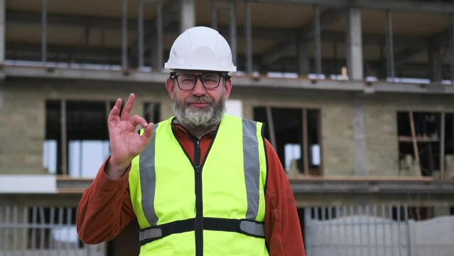 Confident construction worker in safety gear raises his hand with an ok gesture. Teamwork and professionalism in building  industry.