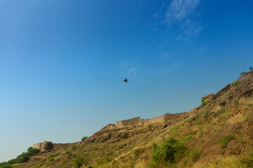 Zipline tourist flying over Rao Jodha Desert Rock Park, Jodhpur, Rajasthan, India. Near the historic Mehrangarh Fort , park contains ecologically restored desert and land vegetation, a tourist spot.