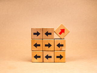 Leadership, unusual, odd, unique, think different way and stand out from the crowd concepts. Red arrows go up diagonally and black arrows indicate directional vignettes on wood cube blocks stack.