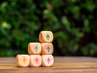 Multi Colors rise up arrows on wooden cube blocks stack, bar graph chart steps on green leaves...