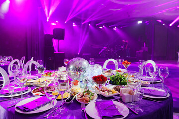A table set for the holiday in purple in a dark banquet hall. 