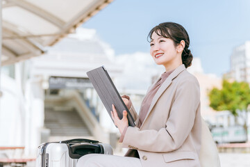 出張先の駅・空港から配車アプリでタクシー・レンタカーを手配する女性（レンタカー・ライドシェア）
