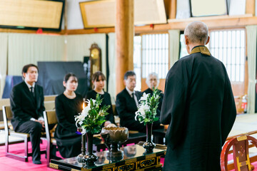 葬式で法話や説教をする住職・お坊さんと遺族（お寺・本堂）
