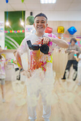 Selfie of a photographer in white clothes smeared with multi-colored paints