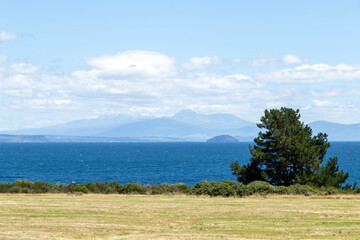 View from Lake Taupo lookout: turquoise waters of the crater lake against the stunning backdrop of the Taranaki Mountains, North Island, New Zealand