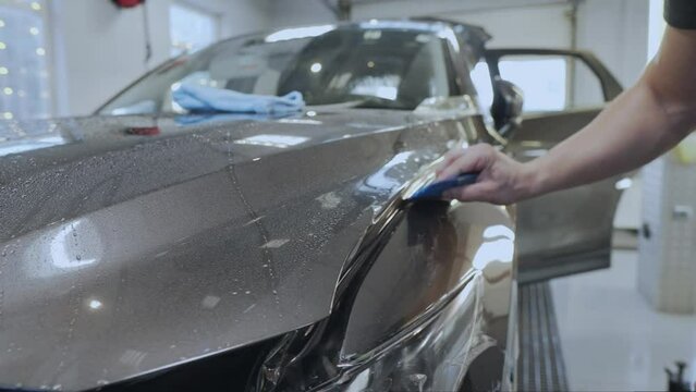 The Hand of the Master Smooths the Armored Membrane on the Surface of the Car, Front Fender. Car Detailing, Wrapping with Membrane Protecting from Stones, Dust, Moisture and Corrosion