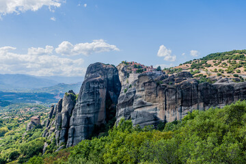 Scenic view of monastery perched atop a rocky mountain surrounded by greenery in Meteora Greece