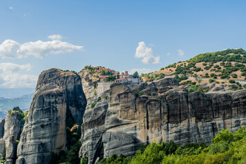 Panoramic view of monastery set high on a rocky crest amidst lush landscapes in Meteora Greece