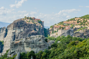 A view of two monasteries atop the stunning cliffs surrounded by lush greenery in Meteora Greece