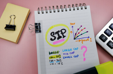 Concept of SIP or Systematic Investment Plan written on note pad while doing planning for investment with graphs.