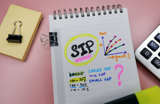Concept of SIP or Systematic Investment Plan written on note pad while doing planning for investment with graphs.