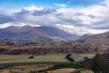 Photograph from Coronet Peak of a mountain range and a large agricultural valley on a cloudy day in Queenstown on the South Island of New Zealand