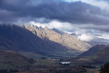 Photograph from Coronet Peak of a mountain range and a large agricultural valley on a cloudy day in Queenstown on the South Island of New Zealand