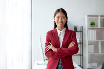 Confident young asian businesswoman in red blazer standing in office. Corporate leadership and...