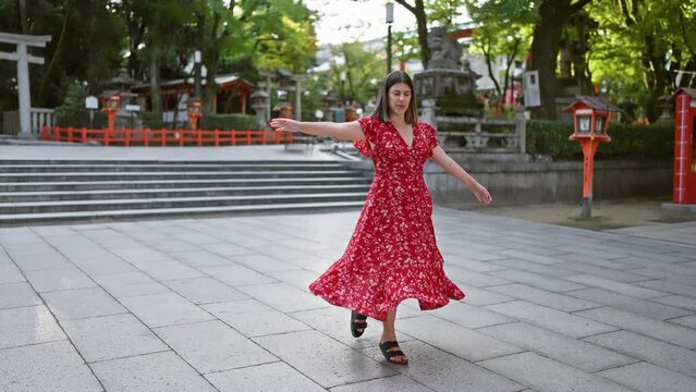 Cheerful beautiful hispanic woman captivatingly spinning around in traditional dress, illuminating the old yasaka temple street, kyoto, with radiance. vacation in japan, freedom embracing dance move.