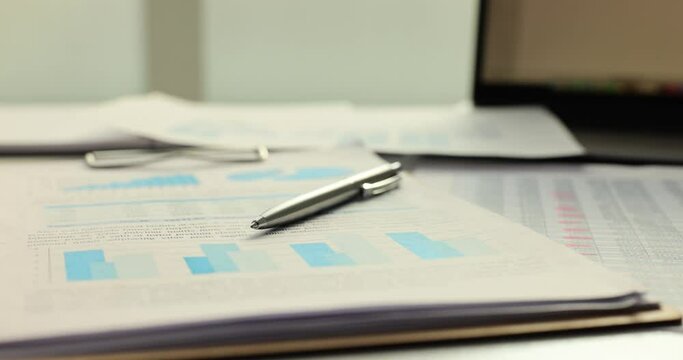 Pen and financial documents and charts on table