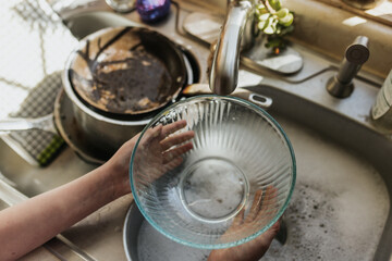Above shot of young girl washing dishes in kitchen sink