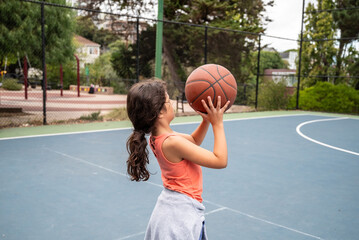 Latina school girl playing basketball at park