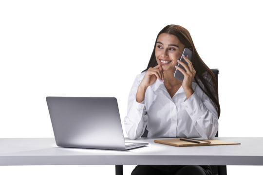 A woman smiles while talking on the phone, with a laptop on the table in front of her, against a white background, depicting a business concept