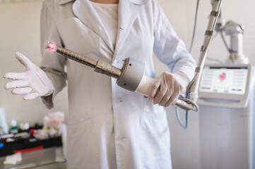 female doctor holds in her hands a carbon dioxide laser with a phallic attachment for vaginal rejuvenation. Hardware cosmetology and medicine. Skin tightening, scar removal, stretch marks and lifting	 - obrazy, fototapety, plakaty
