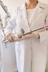 female doctor holds in her hands a carbon dioxide laser with a phallic attachment for vaginal rejuvenation. Hardware cosmetology and medicine. Skin tightening, scar removal, stretch marks and lifting	