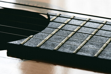 Close up of old acoustic guitar fretboard with selective focus in the center. Neck perspective with blurred sound hole and strings. Music concept. - 783564950