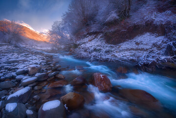 Beautiful mountain rapid river flowing in the evening light, misty, winter season