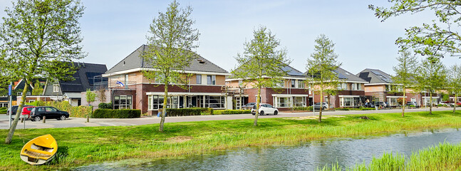 Dutch family street with modern houses with solar panels on the roof, new building with black solar...