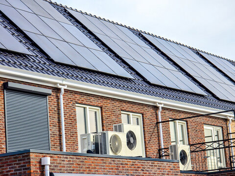 air source heat pump unit installed outdoors at a modern home with solar panels in the Netherlands, Zonnepanelen, Zonne energie, Translation: Solar panel, Sun Energy
