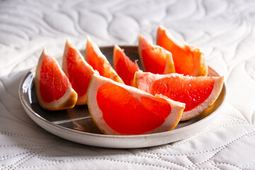Sliced grapefruit on a plate. Red grapefruit slices in dish.