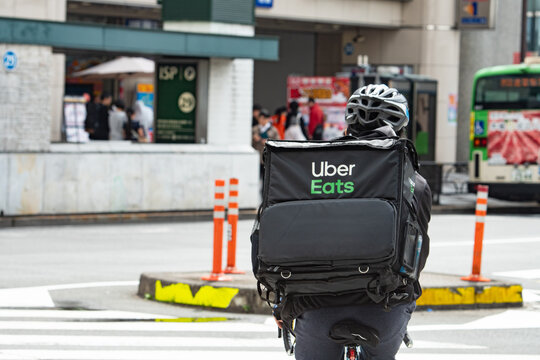 Tokyo, Japan - April, 2024 : Uber Eats rider cycling in the street ,delivery service at Tokyo, Japan.